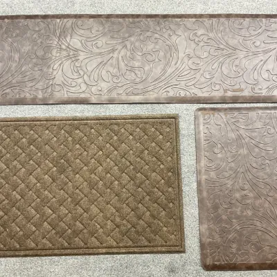 Sale Photo Thumbnail #74: Three brown floor mats, including a long runner and a smaller mat with matching embossed scroll patterns, alongside a textured basketweave-patterned doormat.