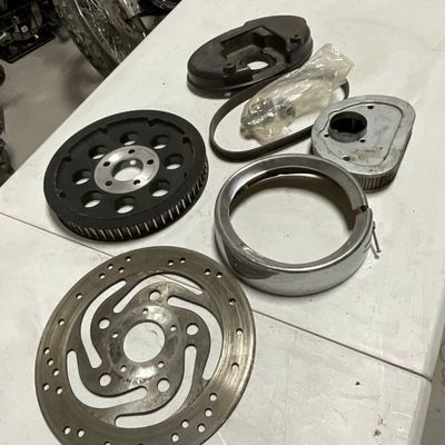 An Assortment of Motorcycle Components Including a Steel Brake Rotor and Drive Pulley