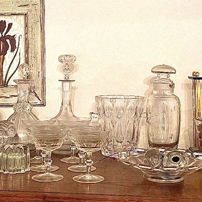 Collection of vintage glassware, including crystal decanters, etched coupe glasses, bowls, and a small framed iris print.