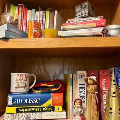 Wooden bookshelf filled with various books, including a Larousse Spanish-English dictionary, alongside decorative items like a vintage...