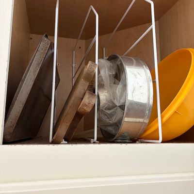 Sale Photo Thumbnail #45: White wire cabinet organizer rack holding a baking sheet, wooden cutting boards, a metal cake pan, and a yellow plastic bowl.