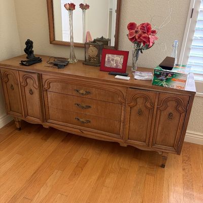 Sale Photo Thumbnail #41: Vintage mid-century French Provincial style wooden credenza featuring three central drawers with ornate brass pulls, flanked by double cabinet doors on each side.