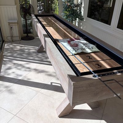 Sale Photo Thumbnail #68: Modern rustic shuffleboard table featuring a light oak-finished wood frame, X-shaped legs, and a glossy butcher block playing surface.