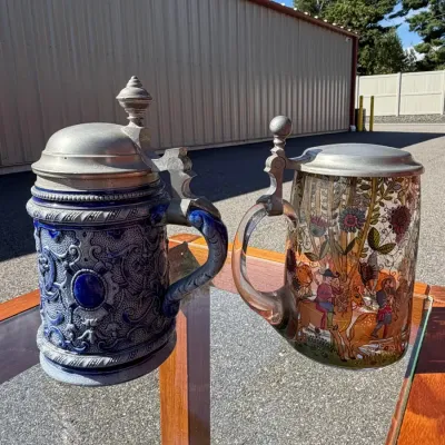 Two distinct styles of traditional German beer steins featuring classic mid-to-late 20th-century