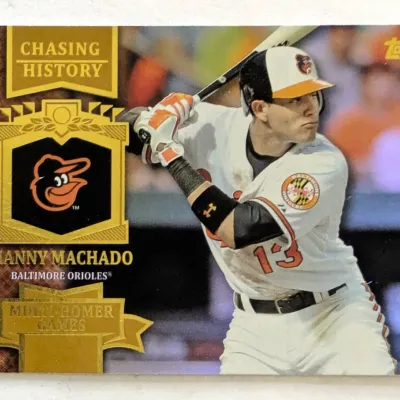 Topps Manny Machado Baltimore Orioles "Chasing History" baseball card, featuring a gold foil design celebrating multi-homer games.