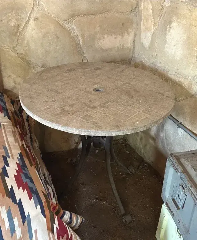 Round Outdoor Patio Table Featuring a Patterned Stone-Look Top and a Central Umbrella Hole