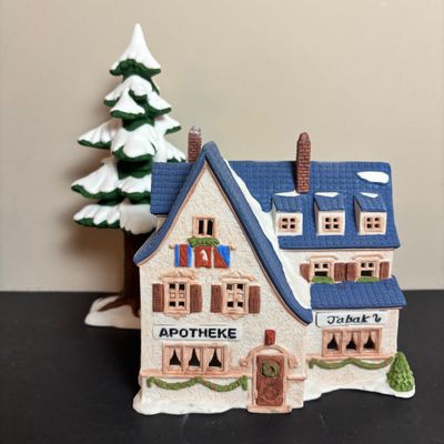 LOT 97: Dept 56 Alpine Village Series: Stoder Grist Mill, Apotek & Tabak along with a Village Porcelain Pine Tree