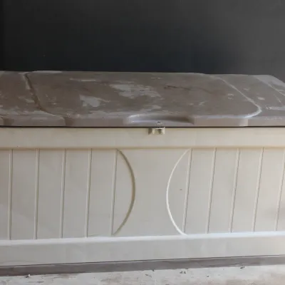 Suncast plastic outdoor deck box with a beige body and a brown lid, showing some wear and weathering.