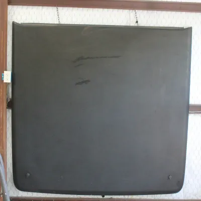 Black fiberglass hardtop for a Jeep or similar utility vehicle, hanging vertically for storage.