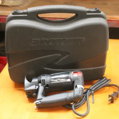 RotoZip spiral saw with its original black hard plastic carrying case, shown on a wooden workbench.