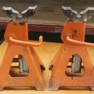Pair of vintage orange steel jack stands showing some wear and paint loss from use.