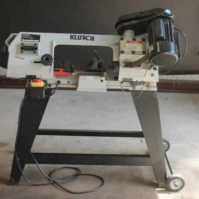 Klutch horizontal/vertical metal-cutting band saw mounted on a black wheeled stand, showing light use.