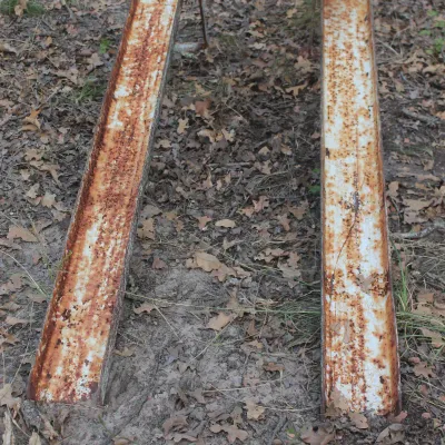 Pair of vintage metal car ramps with significant rust and weathered white paint, showing heavy outdoor wear.
