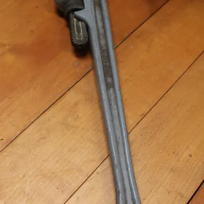 Heavy-duty aluminum pipe wrench with a grey finish, showing some wear from use.