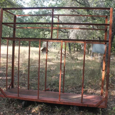 Large, heavy-duty rolling metal rack with a red-painted steel frame, suitable for industrial storage or transport.