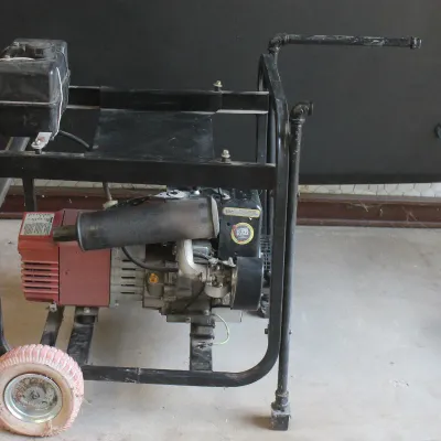 Vintage portable gas generator on a wheeled black metal frame, showing moderate wear from use.