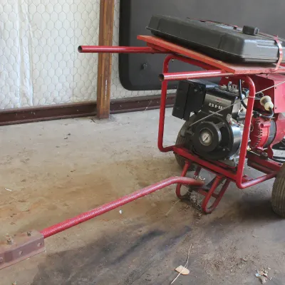 Portable generator with an 8 HP Briggs & Stratton engine, mounted on a red wheeled cart with a tow hitch.