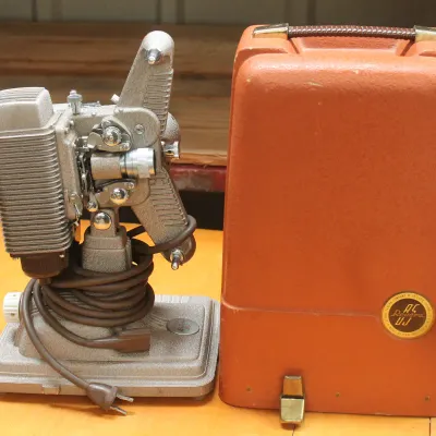 Vintage Revere Model 85 8mm movie projector with its original textured orange carrying case, circa 1950s.