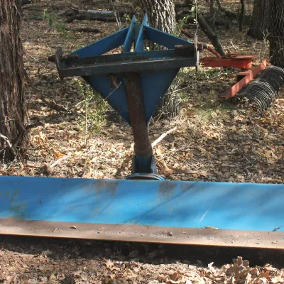 Blue 3-point tractor grader blade showing some wear and rust, 