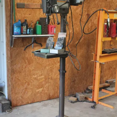 Vintage Sears Craftsman floor-standing drill press, showing some wear from use, accompanied by two cases of drill bits on the work table.