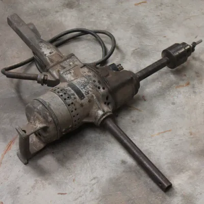 Vintage heavy-duty electric spade handle drill, showing significant wear and patina from industrial use.