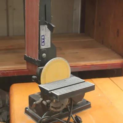 RTC 4-inch belt and 6-inch disc sander combo unit, showing some wear from use, resting on a wooden workbench.