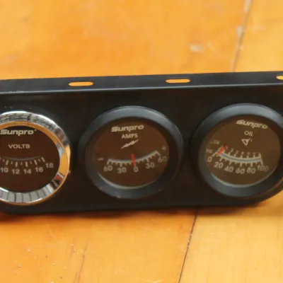 Vintage Sunpro triple gauge set featuring volts, amps, and oil pressure indicators in a black mounting bracket.