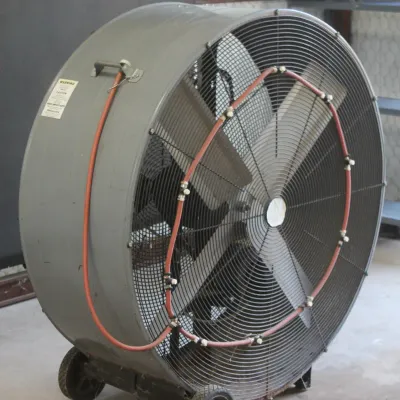 Large industrial drum fan on wheels, featuring an integrated misting ring attachment with red tubing.