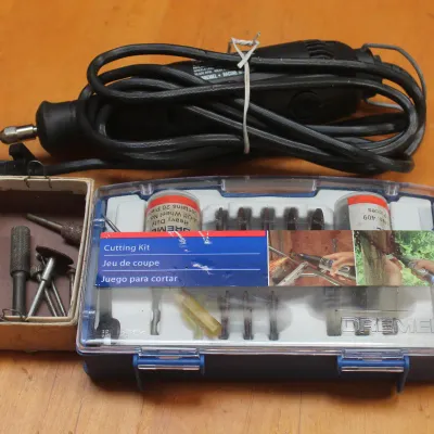 Corded Dremel rotary tool with a small box of loose bits and a packaged Dremel cutting kit.
