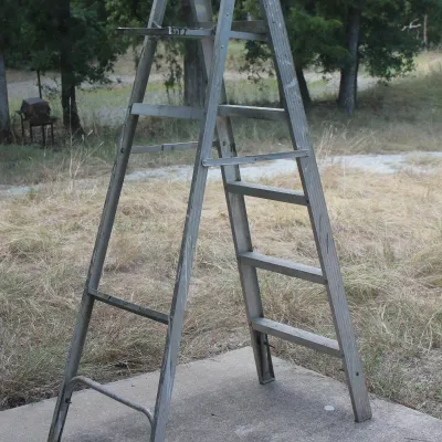 Vintage aluminum A-frame stepladder showing moderate wear and paint splatters from previous use.