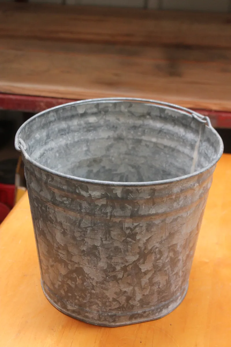 Sale Photo Thumbnail #104: Vintage galvanized metal bucket with a wire bail handle, showing a weathered patina.