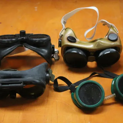 Four pairs of vintage industrial safety and welding goggles in various styles, showing some wear from age and use.