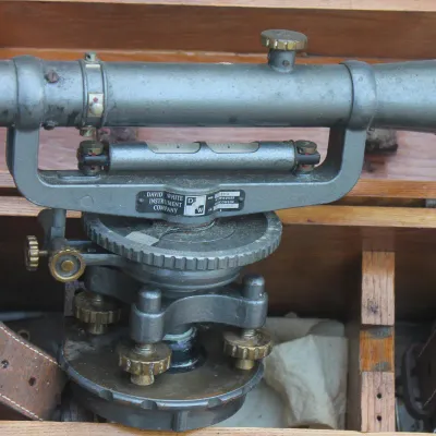 Vintage David White Instrument Company transit level, showing some wear, housed in its original wooden carrying box with leather straps.