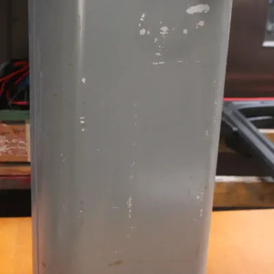 Vintage gray metal fuel tank, possibly for an outboard motor or heater, showing some paint wear and scuffs.