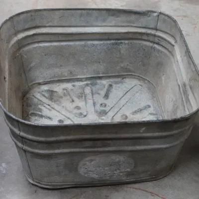 Vintage square galvanized metal wash tub with ribbed sides and a patterned bottom, showing some wear and patina.