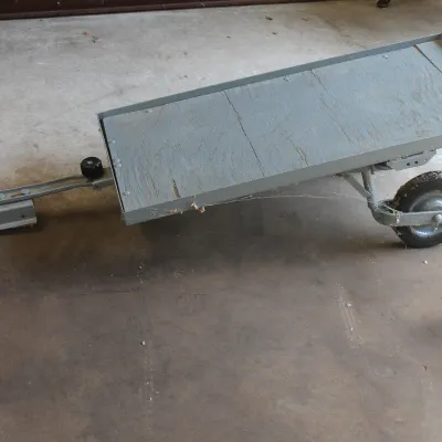 Small utility trailer with a painted gray wooden bed, metal frame, and a standard hitch coupler.