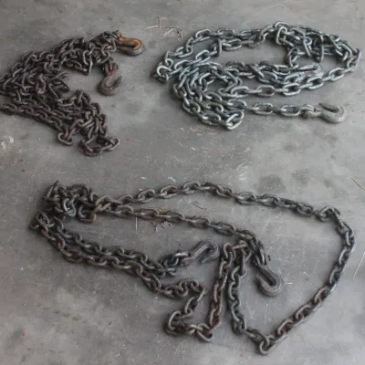Three heavy-duty steel towing and utility chains with grab hooks, showing varying degrees of surface rust and wear.