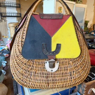 Vintage wicker handbag featuring a color-blocked leather flap in red, yellow, and black with a metal clasp closure.