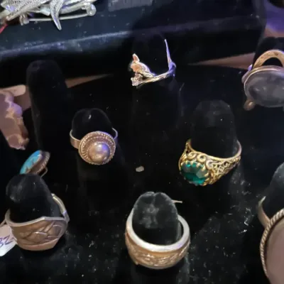 Assortment of vintage rings, including sterling silver, turquoise, and gemstone styles, displayed on a black velvet stand.