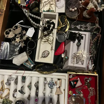 Assortment of vintage and costume jewelry, including rings, necklaces, bracelets, and brooches, displayed in a wooden jewelry box.