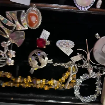 Assortment of vintage costume jewelry, including a tiger's eye chip necklace, silver-tone brooches, a red gemstone ring, and various...