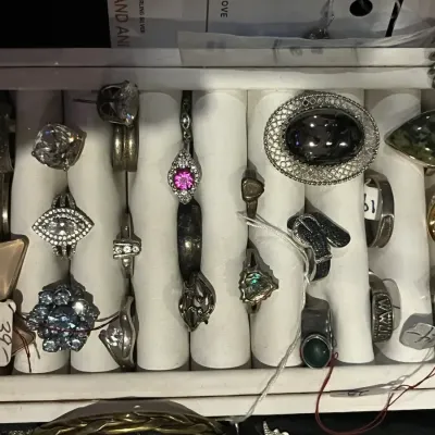 Assortment of vintage and modern rings displayed in a white jewelry tray, featuring various gemstones, metals, and designs.