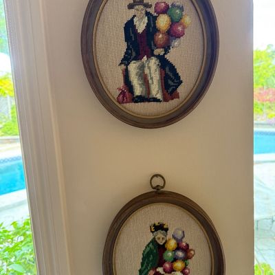 Pair of vintage oval-framed needlepoint pictures depicting a balloon man and a balloon woman, set in dark wood frames with brass hanging...