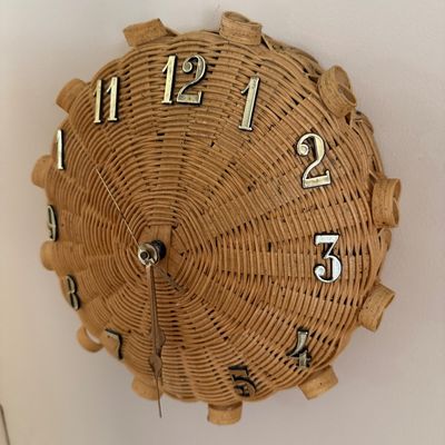Vintage mid-century wicker wall clock featuring a woven dome design with silver-toned metal numerals and hands.