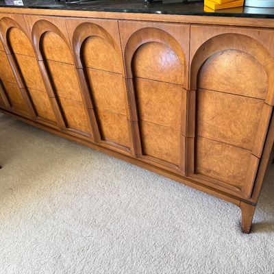 Mid-century modern Broyhill Brasilia style walnut credenza featuring distinctive sculpted arch drawer fronts and a black laminate top.