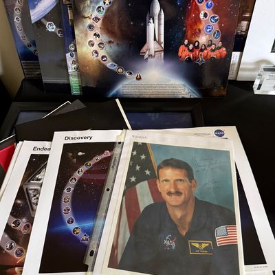 Collection of NASA space shuttle memorabilia, including a signed portrait of astronaut Joseph R. Tanner, mission posters for Discovery...