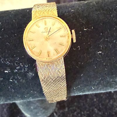 Vintage Omega ladies' wristwatch featuring a gold case and an integrated textured mesh bracelet band.