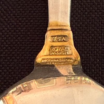 Close-up of the maker's mark on an International Silver sterling silver spoon in the "Royal Danish" pattern, showing...