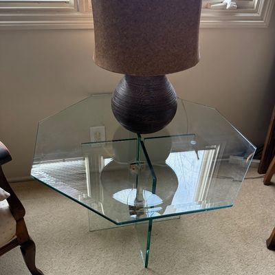 Modern hexagonal glass-top end table with a matching glass pedestal base, topped with a contemporary textured ceramic table lamp.