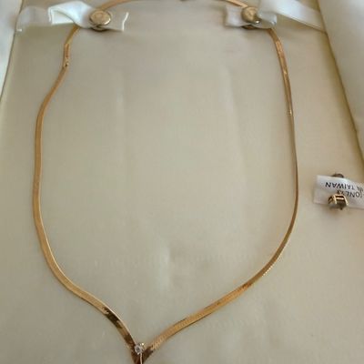 Vintage gold herringbone V-neck necklace with a small central diamond accent, presented in its original cream-colored display box.